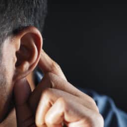 Close up of a man holding his hand to his ear